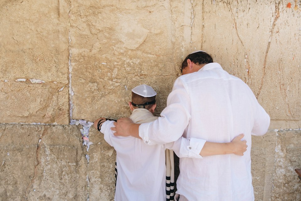 A father hugging his son at the Western Wall on his bar mitzvah