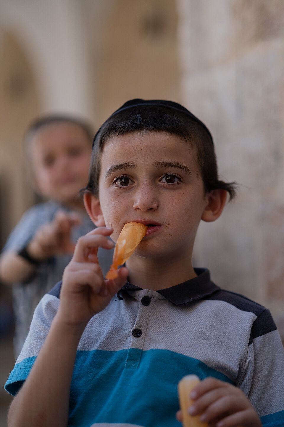 A boy with a kippah eating an ice pop in the Jewish Quarter of Jerusalem