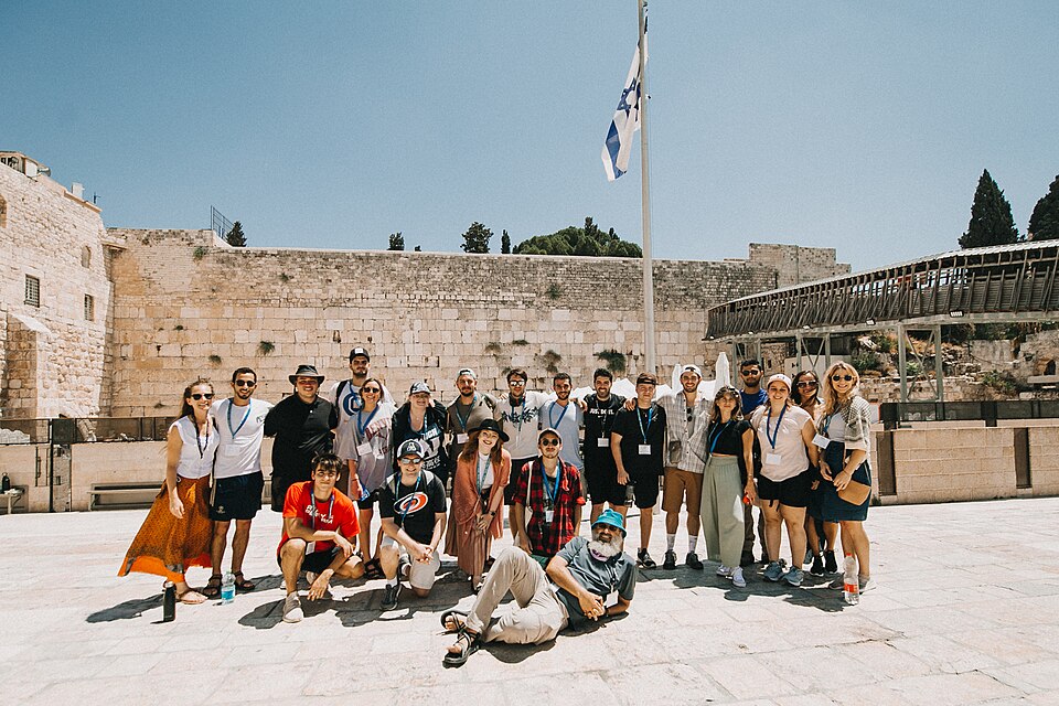 A cheerful group of young Jews at the Western Wall under the Israeli flag
