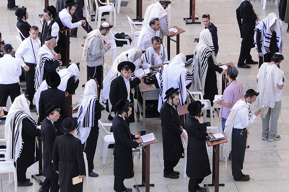 Men in tallit and tefillin at morning prayers at the Western Wall
