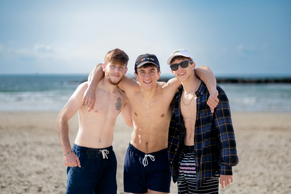 Three smiling young friends on a Tel Aviv beach